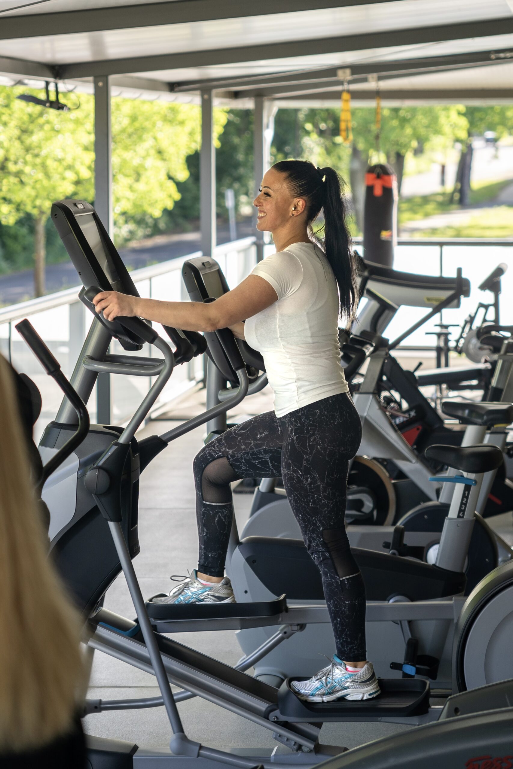 Frau auf Crosstrainer auf Trainingsbalkon